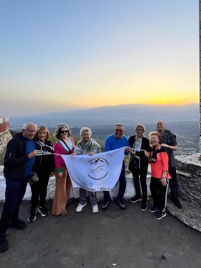 Grupo de viajeros de Huayra Mosoq con la bandera de la agencia al atardecer